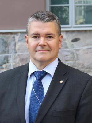 Photograph of the Security Committee's Secretary-General (2020-2023) Petri Toivonen wearing a dark suit and blue tie.